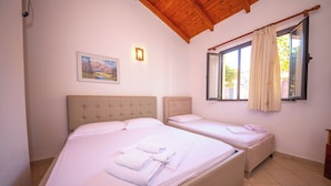 Habitació amb dos llits, un quadre a la paret, una finestra amb cortines i un sostre de fusta.