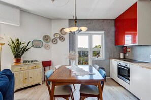 A modern kitchen with a dining table, chairs, and a red cabinet. - Spacious and Bright Apartment II (Porto)