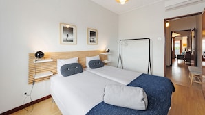 Hotellihuone, jossa on sänky, yöpöydät, työpöytä, tuoli ja näkymä käytävälle.