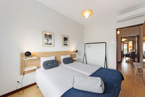 A hotel room with a bed, bedside tables, a desk, a chair, and a view of the hallway. - Spacious and Bright City Apartment – No Elevator (Porto)