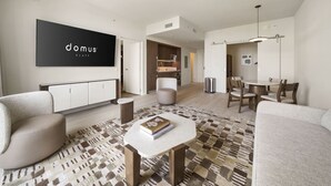 Una sala moderna con un sofá, una mesa de centro, un comedor con sillas, un televisor montado en la pared y una alfombra estampada.