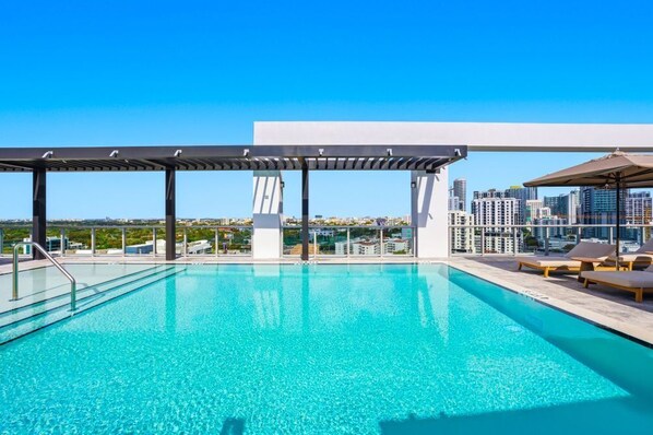 A rooftop pool with a city view, a pergola, and lounge chairs. - Miami Modern 2BR Condo w Pool, Gym. Relax & Revive (Miami)