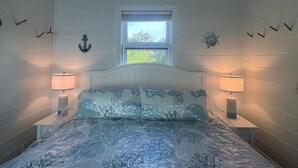 Un dormitorio con cama, dos lámparas de noche, una ventana y adornos en la pared.