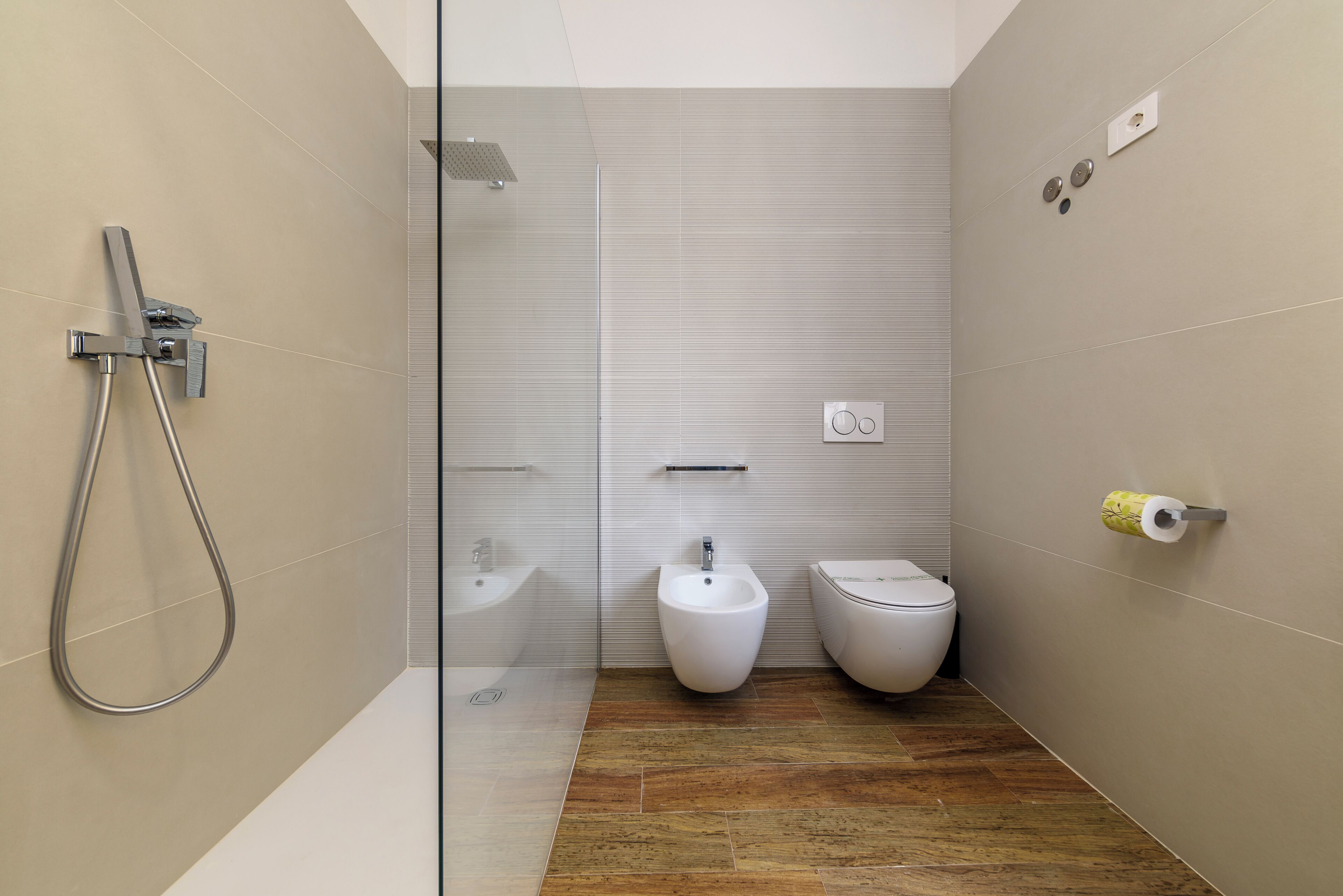 Une salle de bain moderne avec une douche à parois de verre, un bidet et des toilettes.