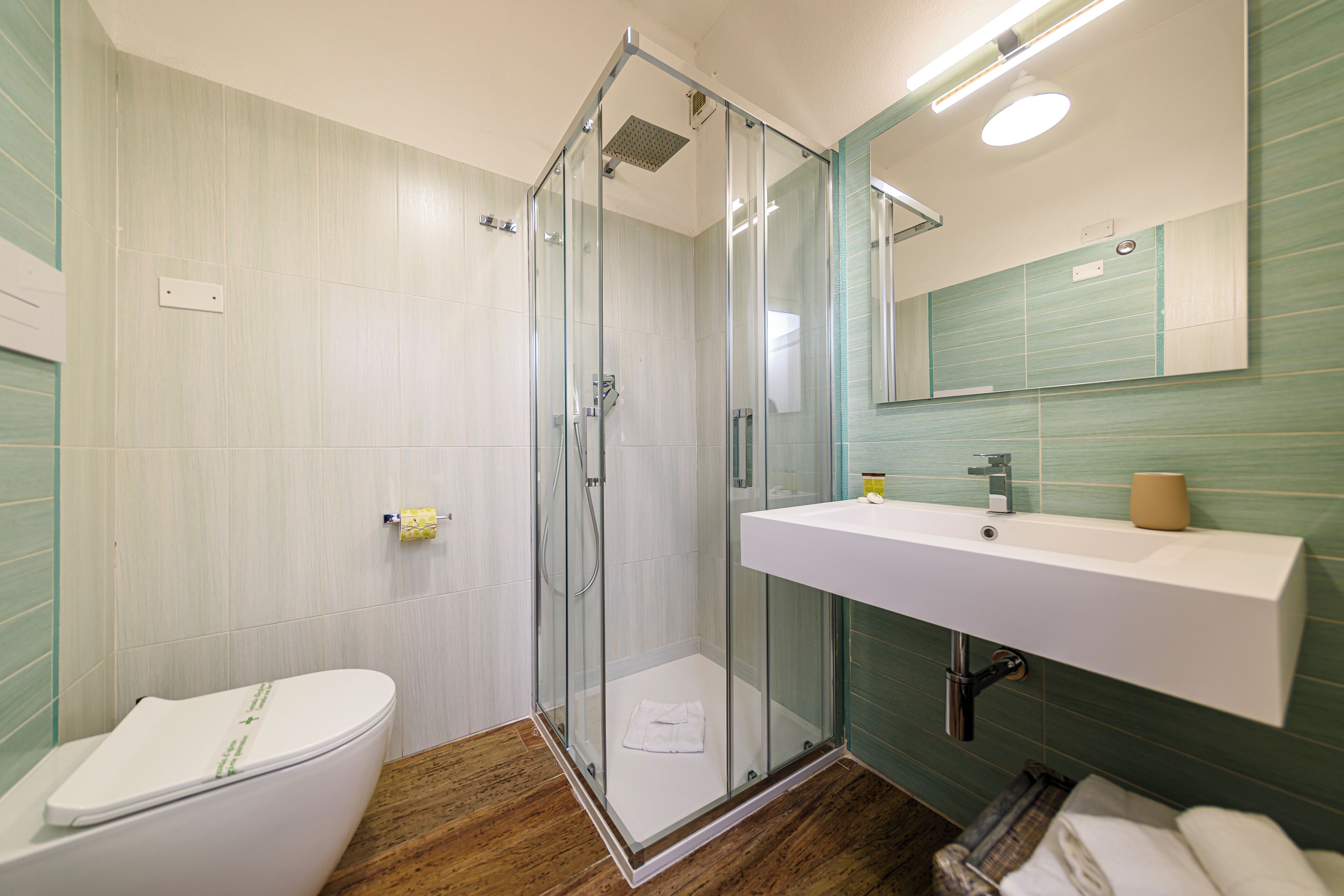 A bathroom with a glass-enclosed shower, a white sink, and a toilet.