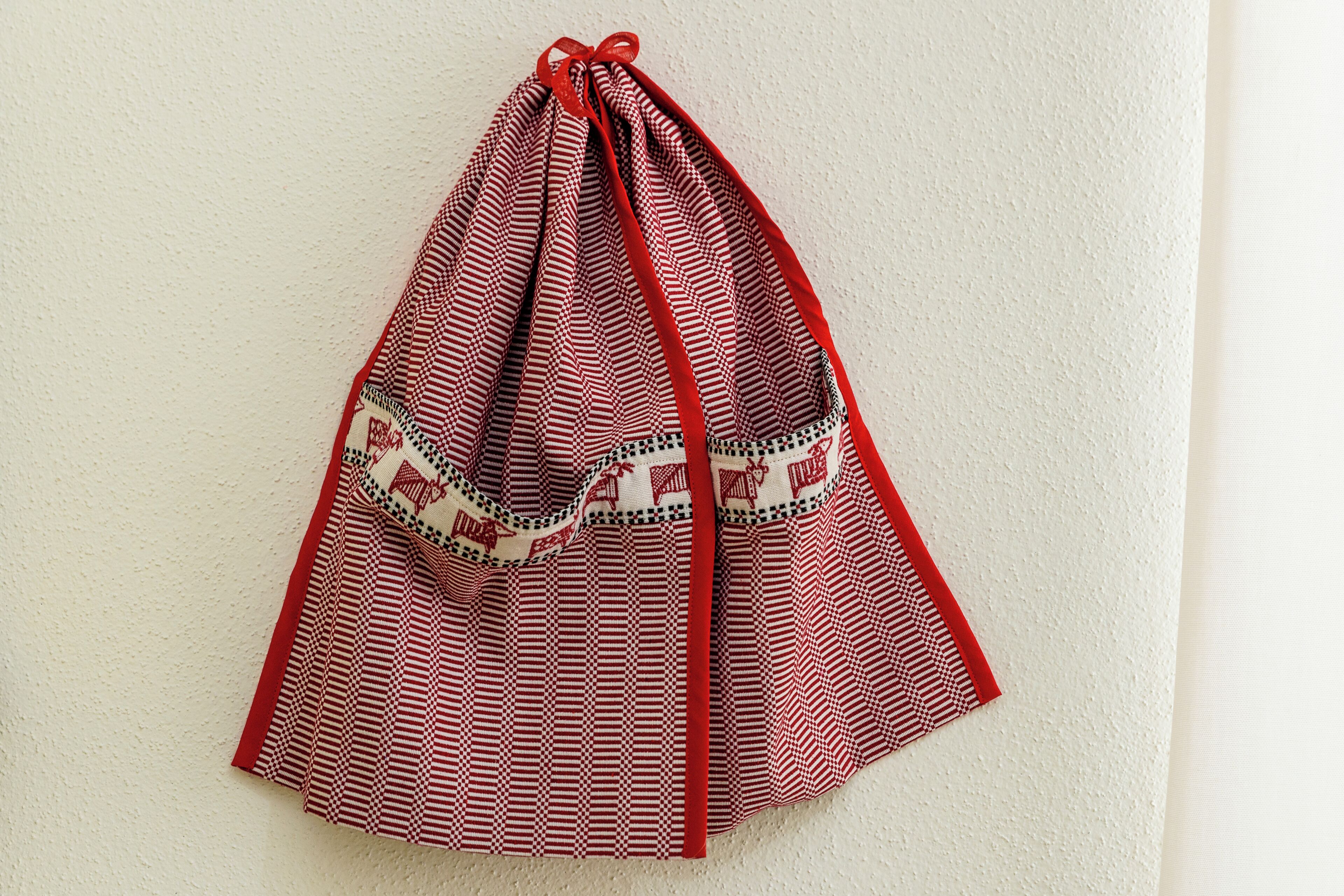 Un trozo de tela rojo y blanco con un estampado que cuelga de una pared.