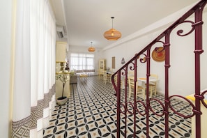 Eine Treppe mit einem gemusterten Boden, ein Essbereich mit Stühlen und einem Tisch, sowie ein Blumentopf.