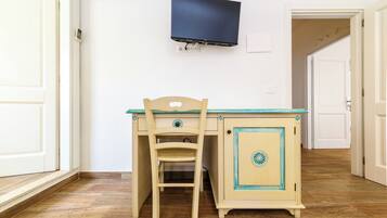 A room with a desk, chair, TV mounted on the wall, and a door.
