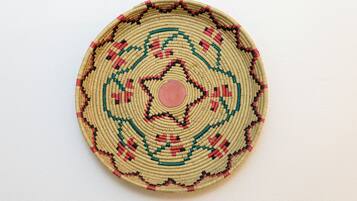 A circular woven object with a central pink dot and a geometric pattern.
