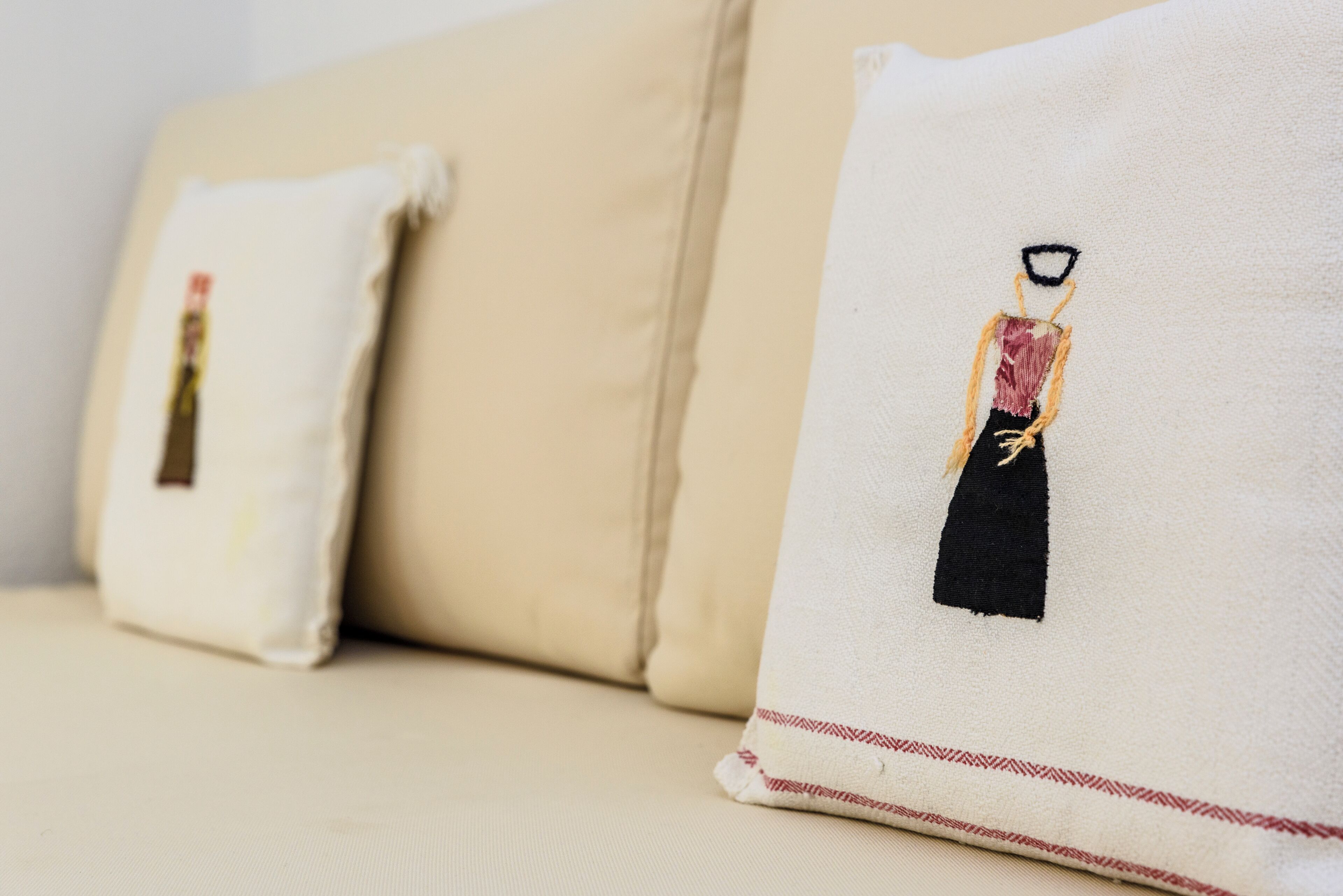 A beige sofa with two pillows, each featuring a black and red design.