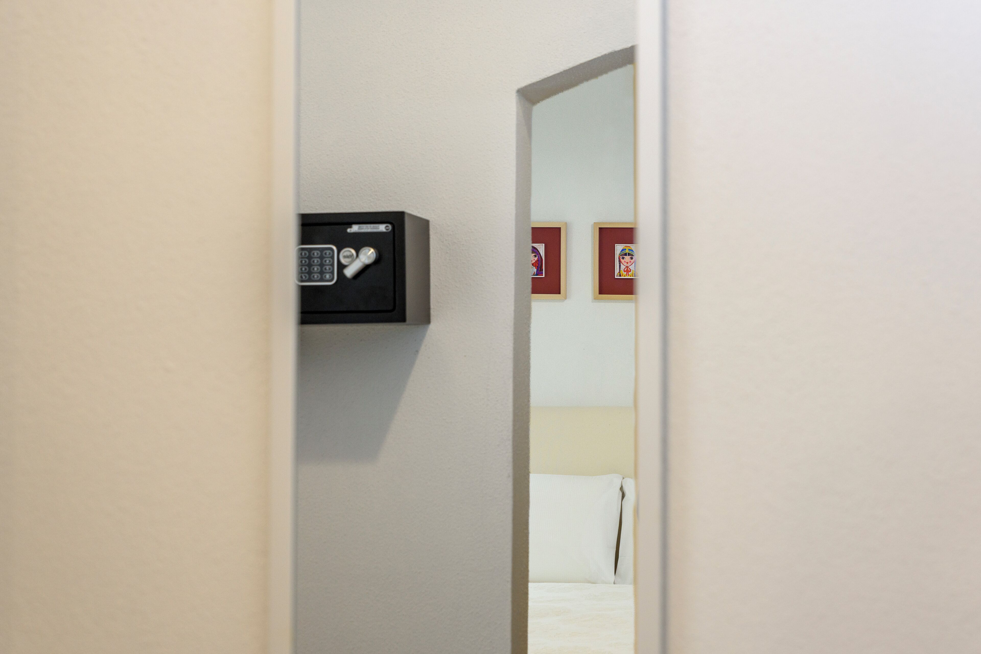 Une chambre d’hôtel comprenant un lit, une table de chevet et un coffre-fort fixé au mur.