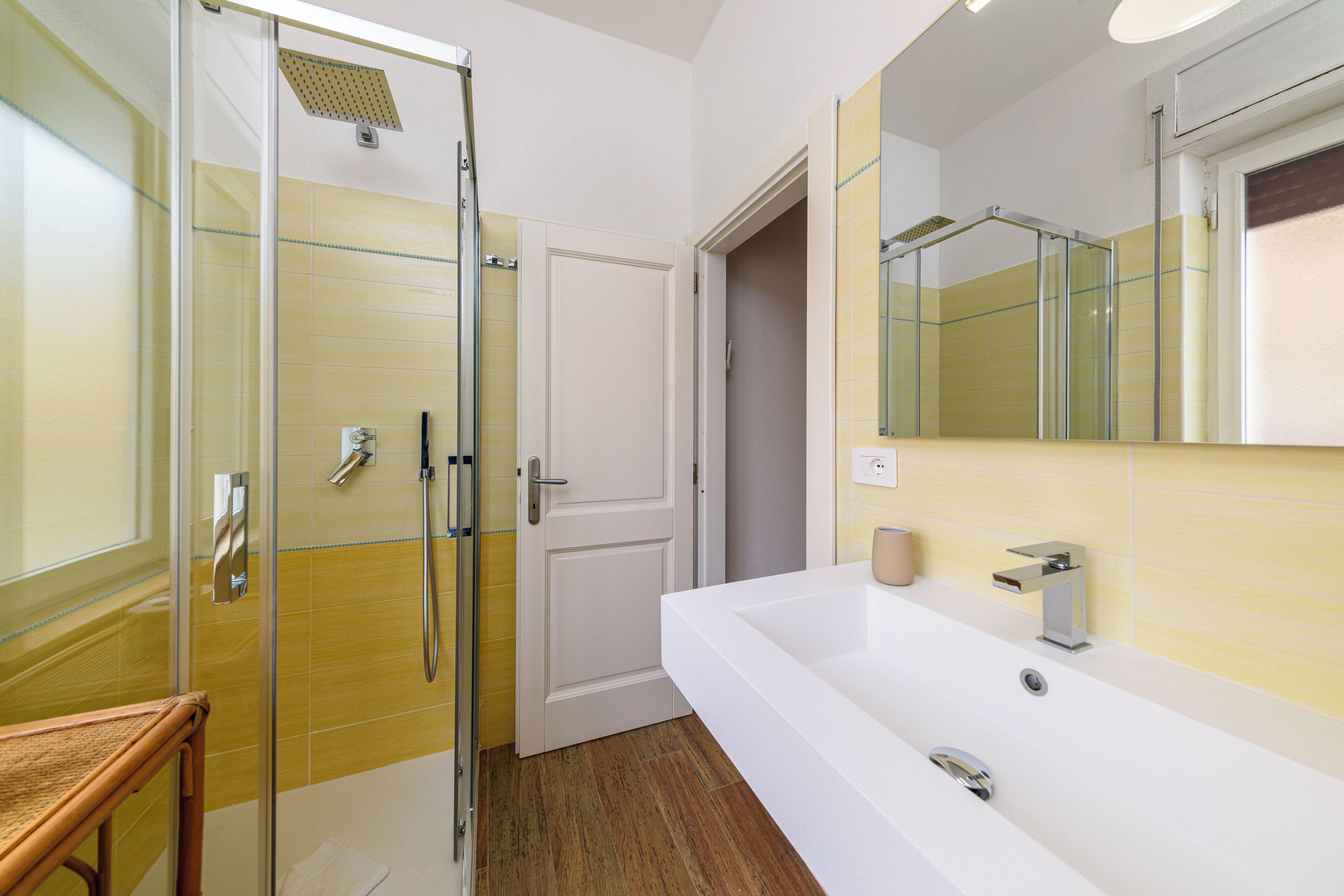 A bathroom with a glass-enclosed shower, a white sink, and a mirror.