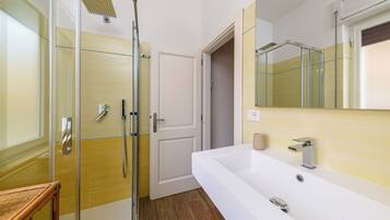 A bathroom with a glass-enclosed shower, a white sink, and a mirror.