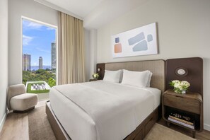 A hotel room with a large bed, a view of the cityscape, a side table with a vase of flowers, and a window with curtains. - Modern 1BR Retreat in Miami – Bay Views (Miami)