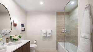 A modern bathroom with a large mirror, two sinks, a toilet, and a glass-enclosed shower area. - Modern 1BR Retreat in Miami – Bay Views (Miami)