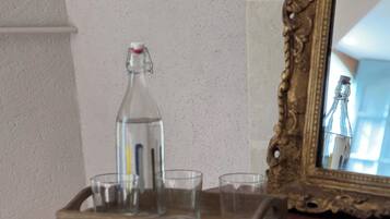 Un plateau en bois avec une bouteille en verre et trois verres posés sur une table.