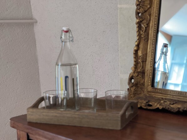A wooden tray with a glass bottle and three glasses on a table. - Le Clos Marie 49 (Mazé-Milon)