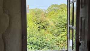 Une pièce avec une seule fenêtre, un tableau encadré appuyé contre le mur et un chambranle de porte visible.