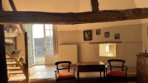 Une pièce rustique avec des poutres apparentes, un escalier en bois, une table à manger avec des chaises et un radiateur.