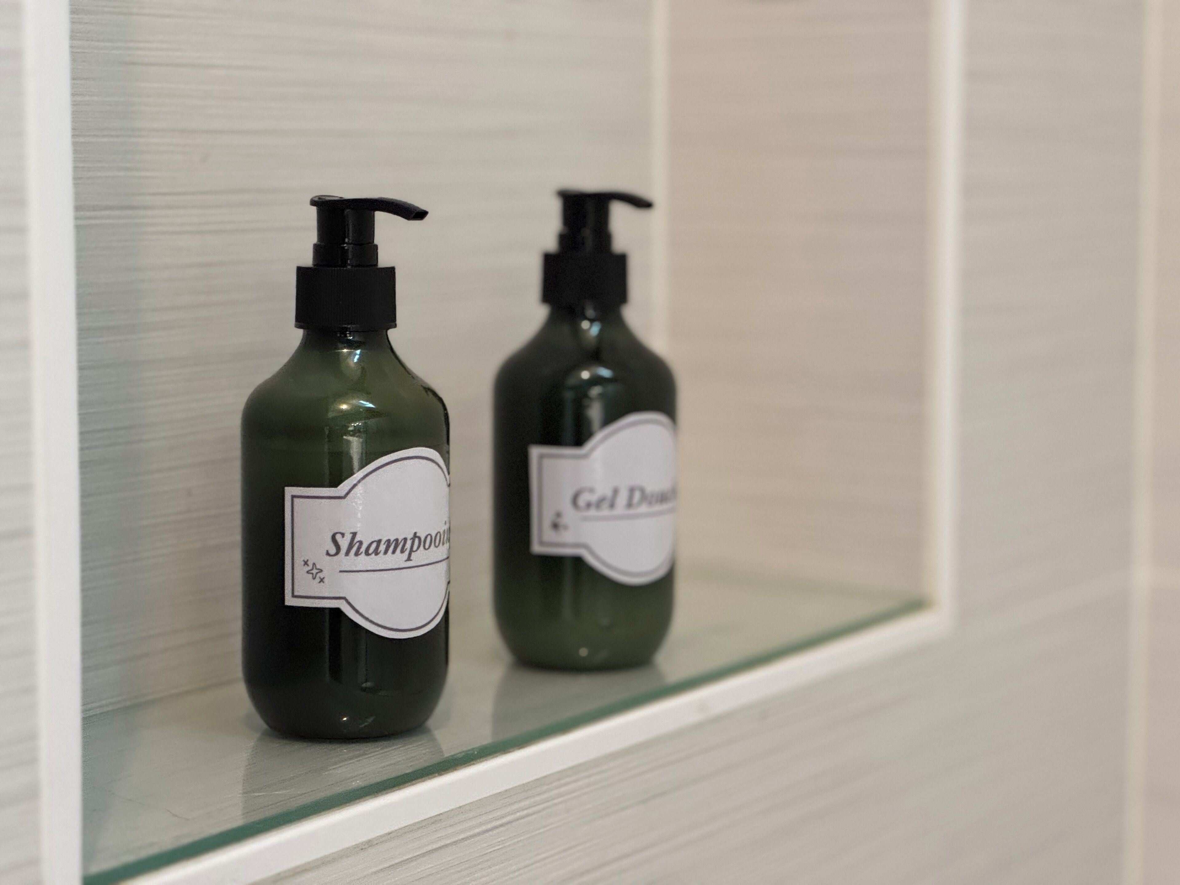 Zwei Shampooflaschen und eine Gel-Flasche auf einem Regal.
