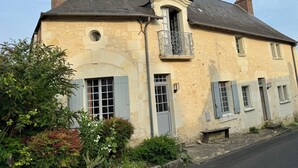 Un bâtiment à deux étages doté d’une façade en pierre, d’un balcon orné de rampes en métal ouvragé et d’une cheminée.