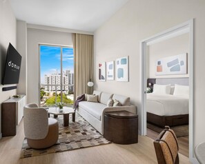 Een moderne hotelkamer met een bank, fauteuil, salontafel en een bed.