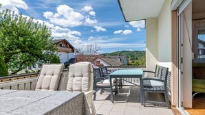An outdoor patio with a table and chairs, a view of houses, and a clear sky.