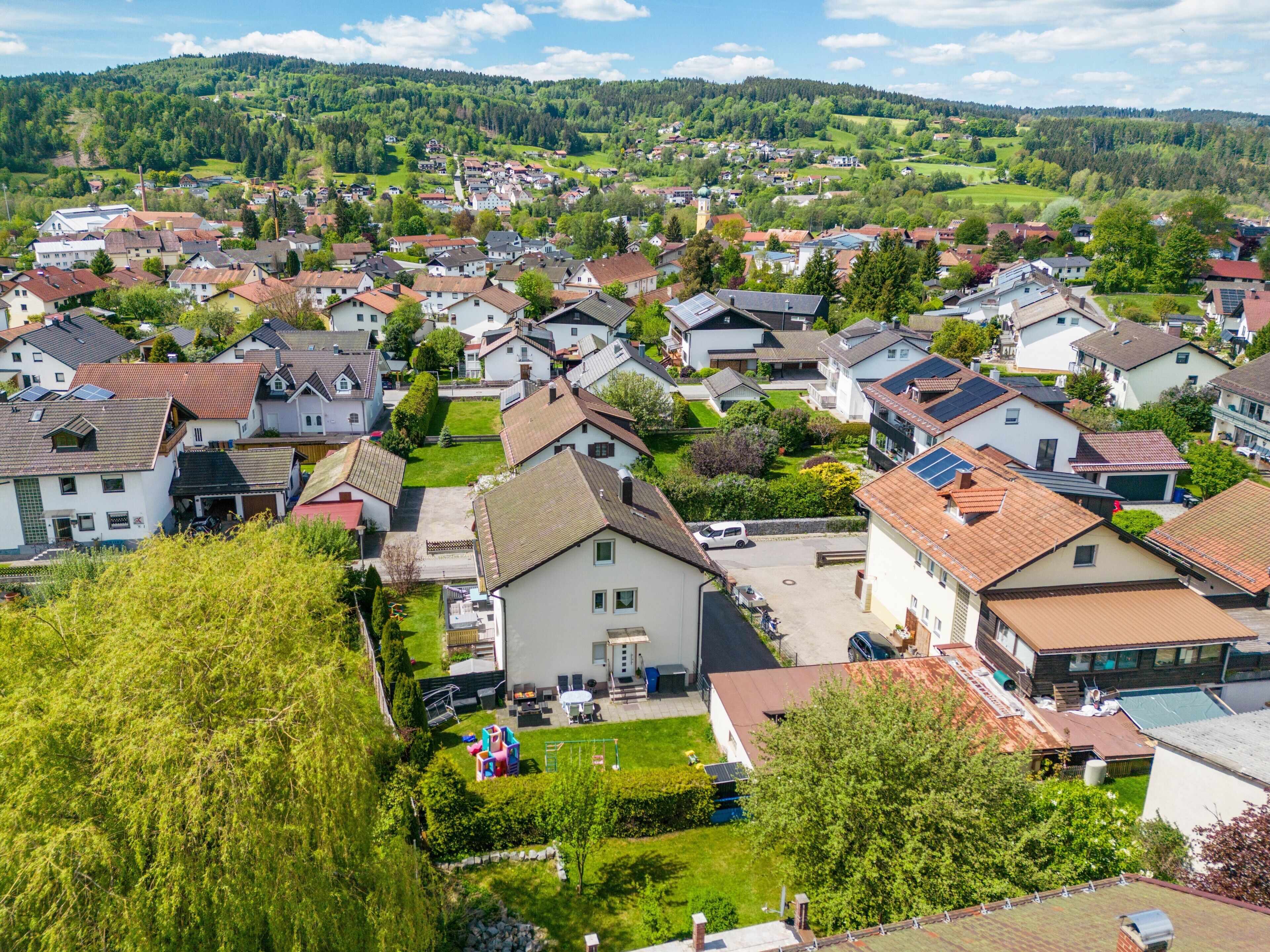 A residential area with houses, a playground, and a large building with a flat roof.