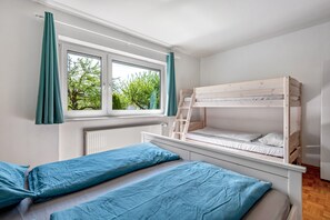 Quarto com beliche, janela com cortinas e radiador.