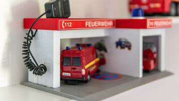 Un modellino di una caserma dei pompieri con un furgone rosso, un camion dei pompieri e un edificio rosso e bianco con la scritta 'FEUERWEHR'.