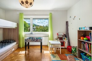Una habitación infantil con cama, mesa, zona de juegos y estantería.