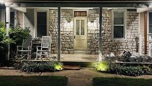 A stone house with a front porch, a door, and two windows. - Labby's Homestead Farmhouse (Hermann)