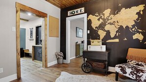 A room with a wooden ceiling, a world map on the wall, a suitcase, and a cowhide rug. - Labby's Homestead Farmhouse (Hermann)