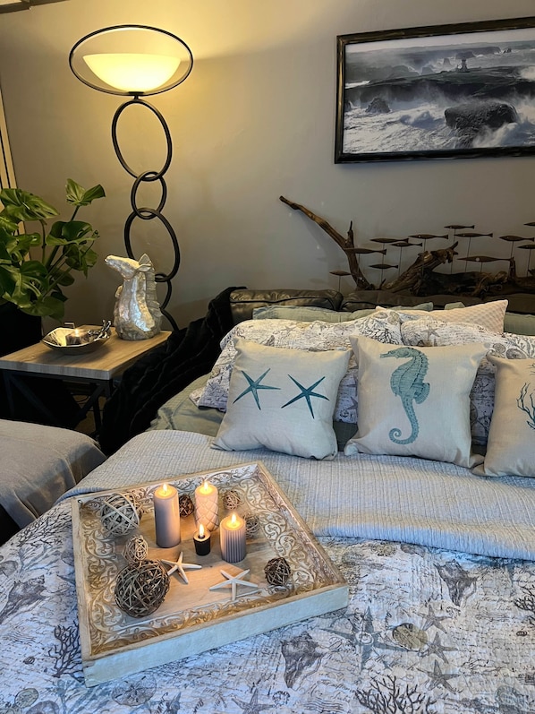 A bedroom with a bed, a nightstand, a lamp, a wall-mounted picture, and decorative pillows.