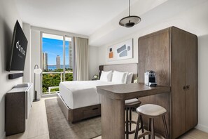 A hotel room with a bed, a desk, a chair, a wardrobe, a TV, and a view of the cityscape. - Chic Studio Escape – Gym, Pool & Balcony in Miami (Miami)