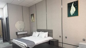 Et moderne hotelværelse med seng, sengeborde, skrivebord, stol og et billede hængende på væggen.