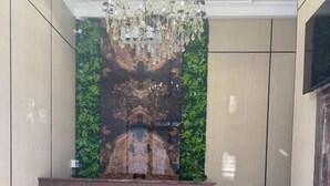 En lobby med reception, sofa, lysekrone og en væg med lodret have.