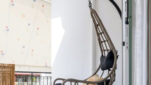 A hanging chair in a room with a white wall and a window with a floral pattern. - Spacious 144sqm flat near Mount Ymittos (Elliniko-Argyroupoli)