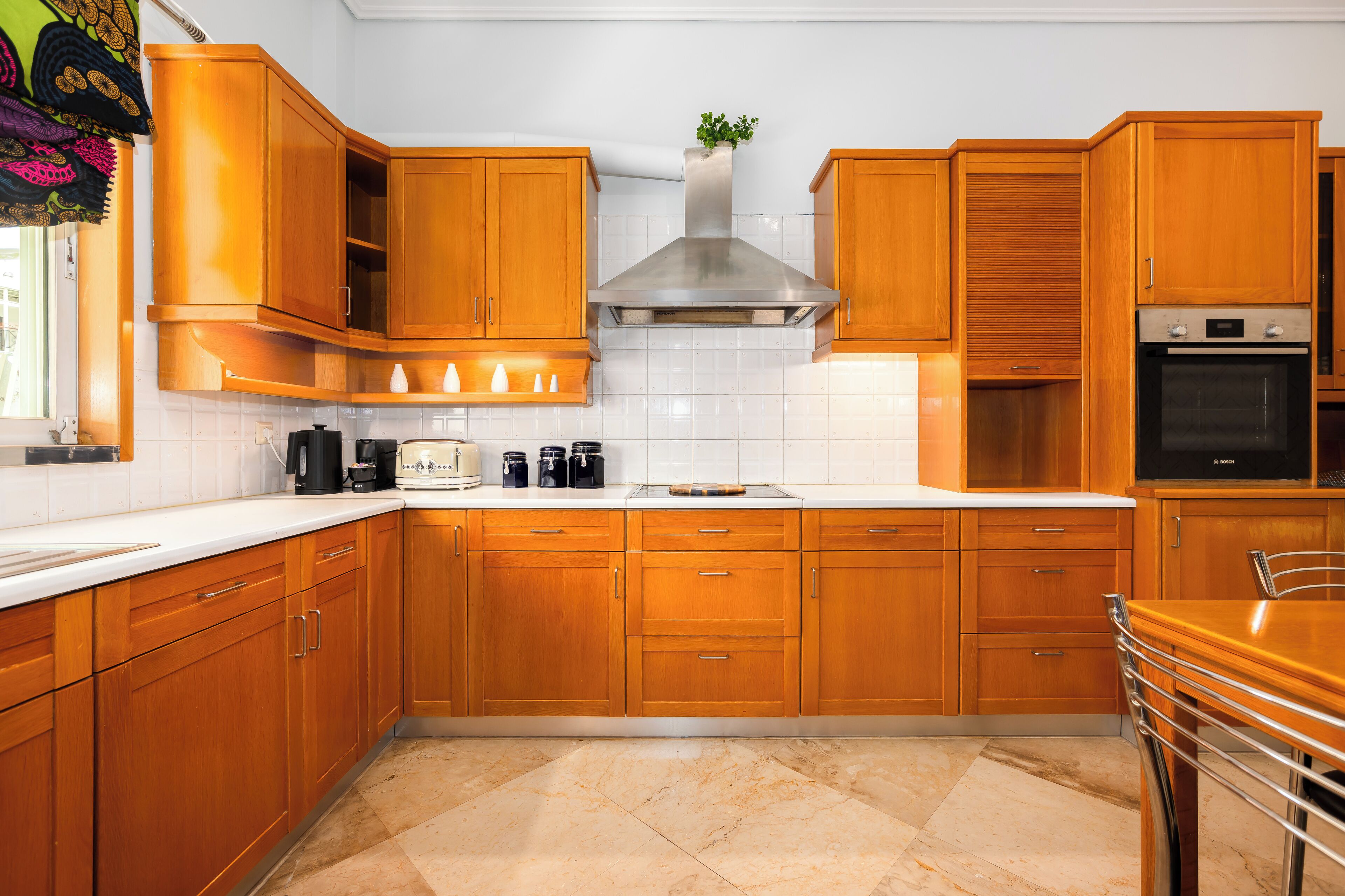 A kitchen with wooden cabinets, a stainless steel range hood, and a built-in oven.