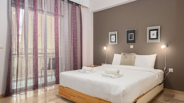 A bedroom with a bed, curtains, wall-mounted lights, and framed pictures. - Spacious 144sqm flat near Mount Ymittos (Elliniko-Argyroupoli)