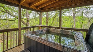 Un jacuzzi en una terraza de madera con vista a árboles.