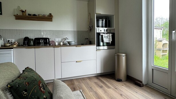 Una cocina moderna con armarios blancos, una estufa de acero inoxidable y una ventana a la derecha.