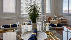 Een eettafel gedekt voor zes personen, met helder glaswerk, een middelpunt en een modern interieur met grote ramen.