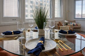 A dining table set for six with clear glassware, a centerpiece, and a modern interior with large windows. - Ste 717-Free Parking + Skywalk Access + Downtown 2BR City Views (Indianapolis)