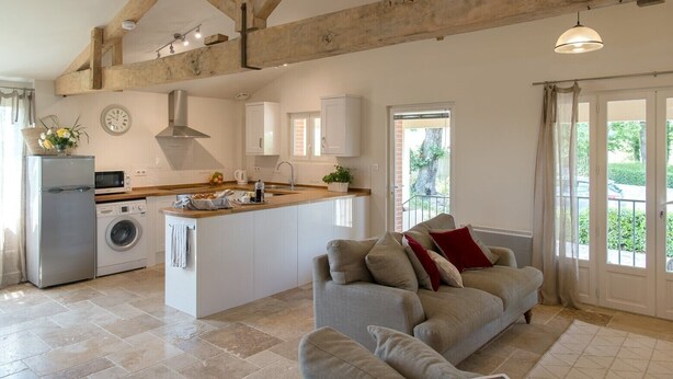 A spacious kitchen with a central island, a built-in washing machine, and a dining area with a sofa.