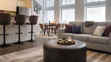 A modern living room with a sofa, ottoman, and bar stools.