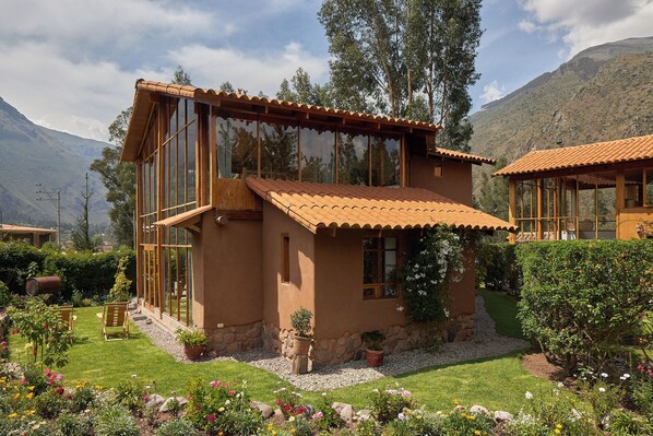 A rustic house with large windows, a stone foundation, and a well-maintained garden.