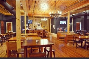 A restaurant with wooden tables and chairs, a bar area, and a television screen. - Elegant Modern Space in Historic City Square (Mobile)