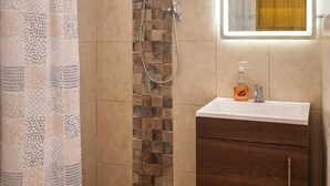 A shower with a glass door, a wooden cabinet with a mirror, and a towel rack. - Los Cipreses Hotel de Montaña (Los Naranjos)