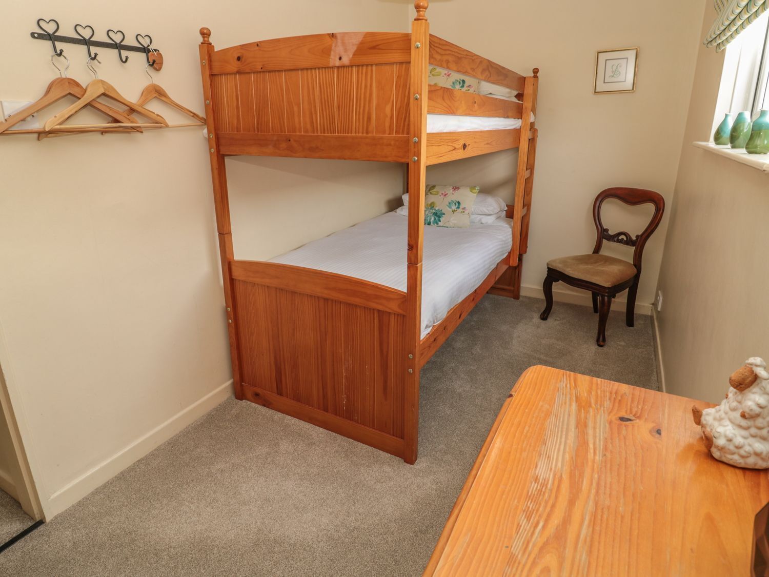 A bunk bed room with a wooden table and a chair.